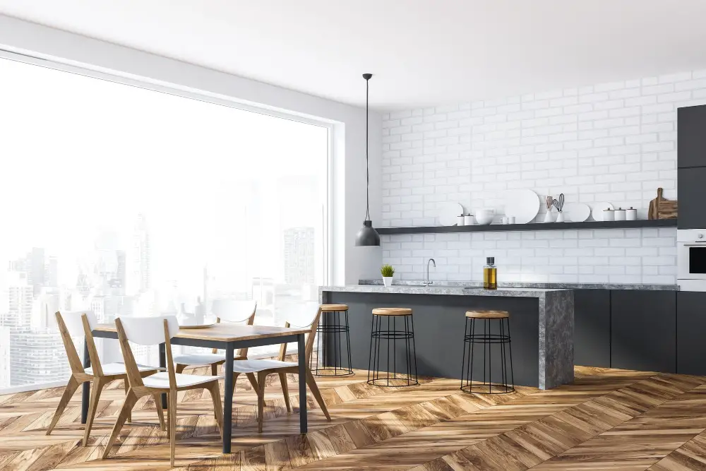 white brick walls wooden floor panoramic window gray and marble countertops wooden chairs and stool 